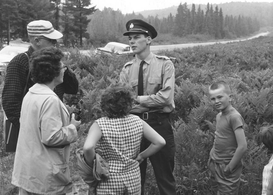 Black and white photograph of a park interpreter with a group on a guided hike in Algonquin Provincial Park.