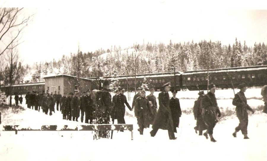 sepia photo of POWs walking off of train at Neys