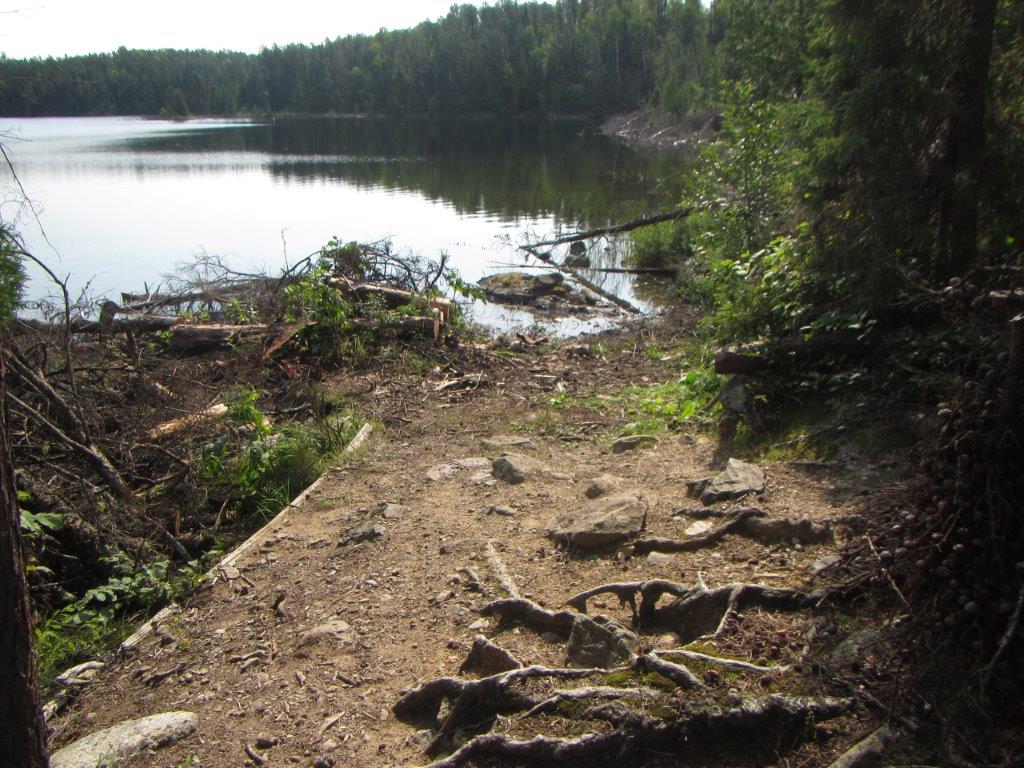 Large dirt-covered area beside lake