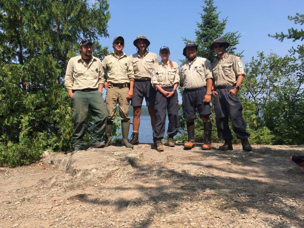 Six personnes portant un uniforme de Parcs Ontario se tiennent debout sur une roche 