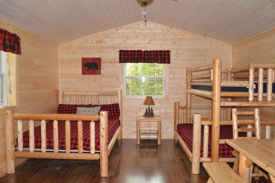 wooden cabin with bunk bed, table, and large bed