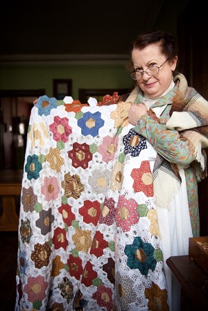 Victorian dressed woman holding quilt