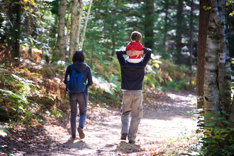Homme avec un enfant sur les épaules, en randonnée en compagnie d’une femme