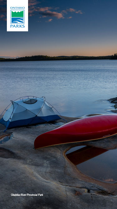 Canoe and tent on shore during sunset.