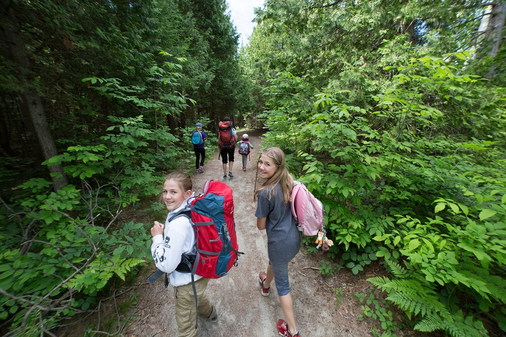 Two kids look back as they hike a trail