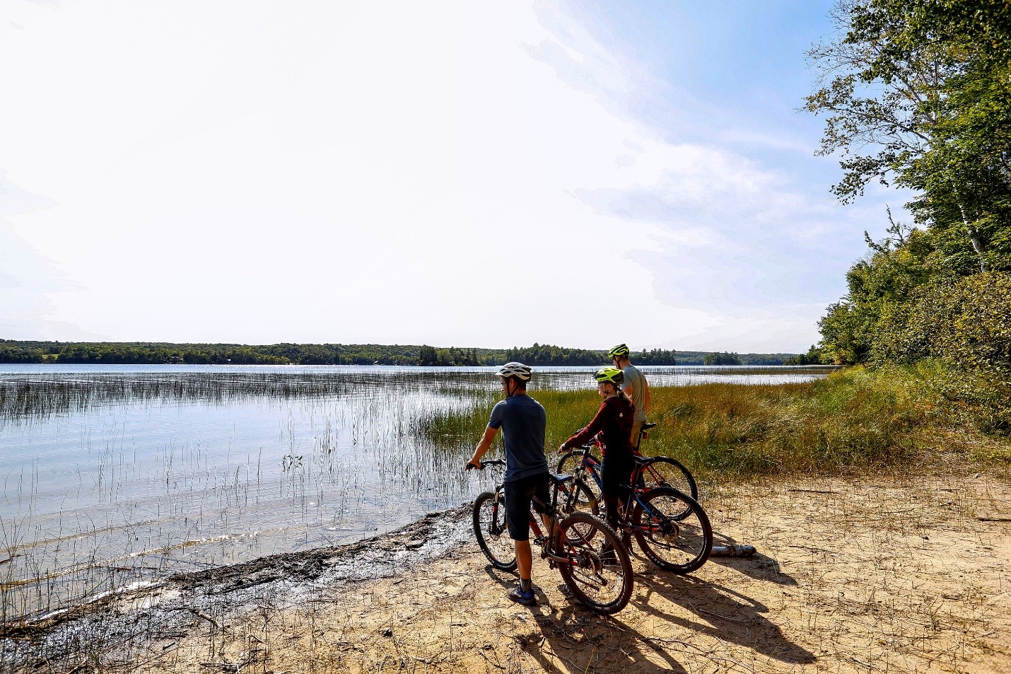Trois personnes en vélo au bord de l'eau regardant à l'horizon