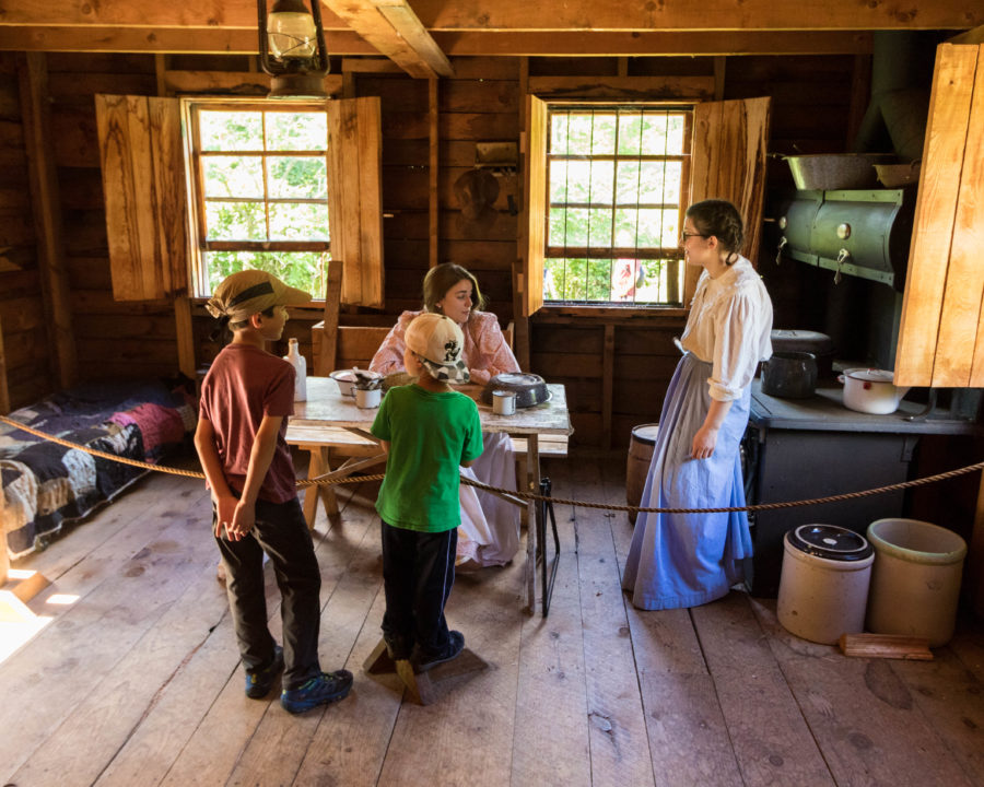 Children talking to staff members dressed in period costume at the farmhouse.