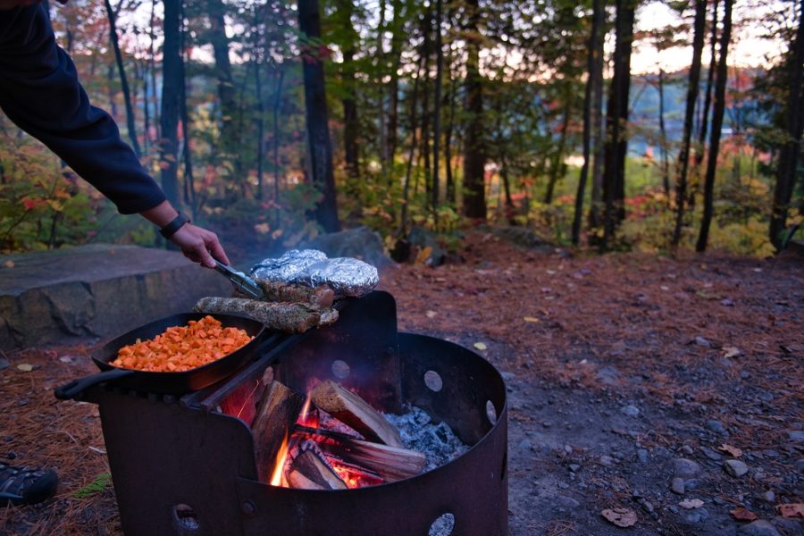 person cooking over campfire