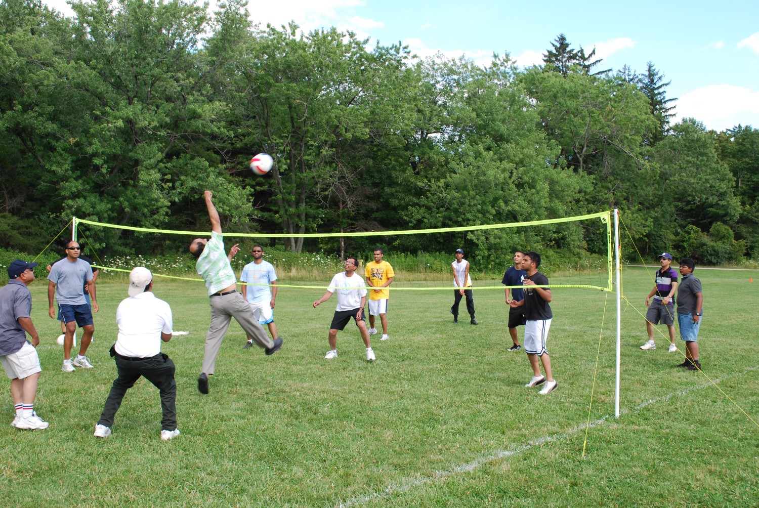 Des personnes jouent au volley-ball sur un terrain gazonné.