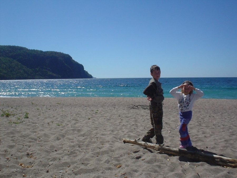 Kelly et son frère aîné debout sur un rondin sur la plage de la baie Old Woman.