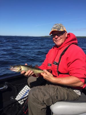 Joe siting in the boat with a 14” White Lake Walleye