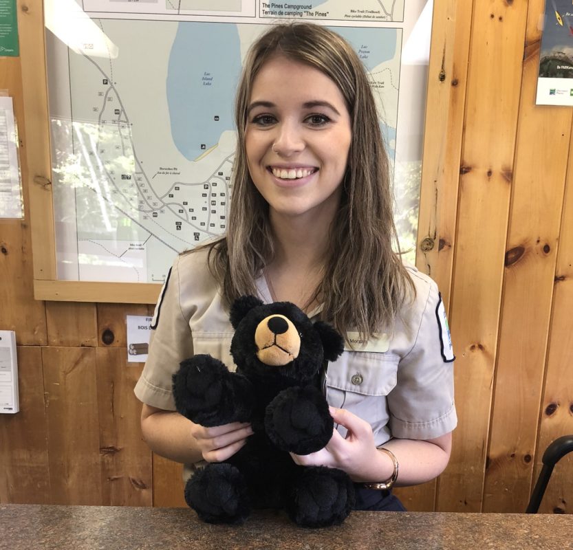 staff holding stuffed animal behind desk