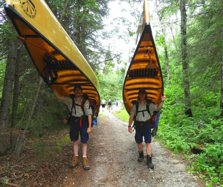 two staff portaging canoes