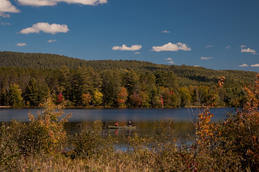 Canot sur l’eau entourée des couleurs de l’automne.