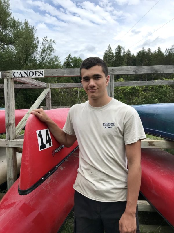 student standing in front of canoe rack