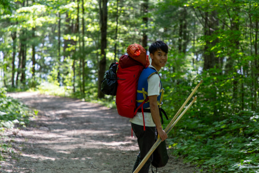 man carrying backpack and paddles