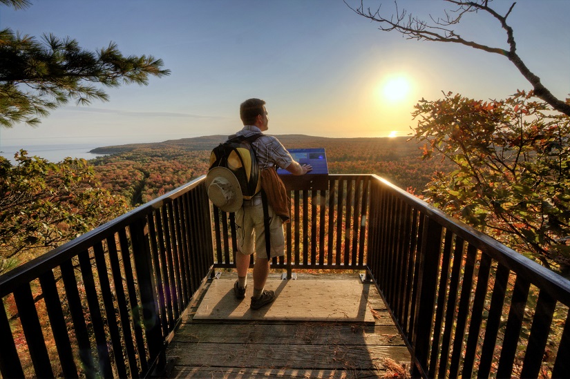 Hiker at lookout over fall trees.