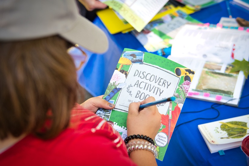 Child writing on Discovery Activity Book.