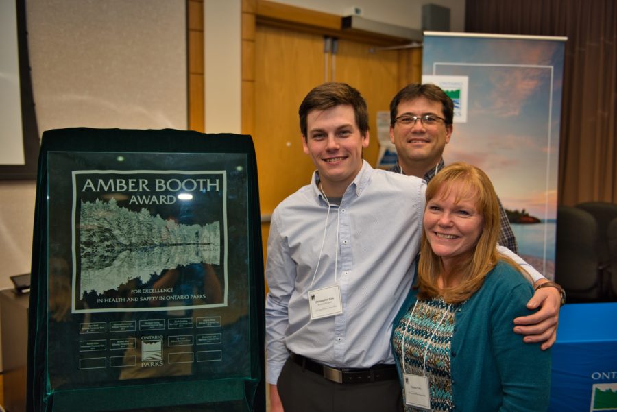Chris poses with his family and the Amber Booth plaque