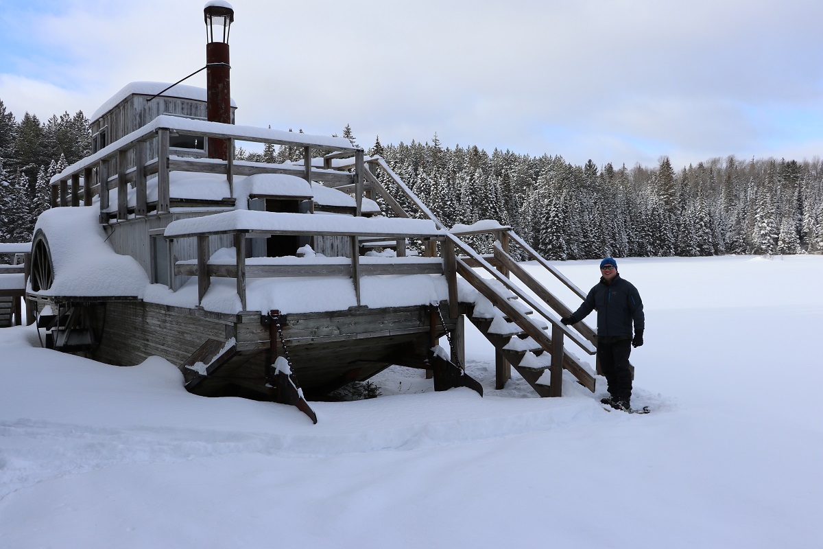 Un homme à côté d’un bateau recouvert de neige au parc provincial Algonquin
