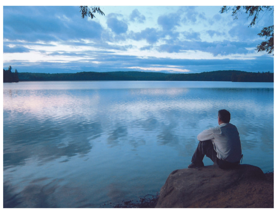 Un homme assis près de l’eau regardant au loin