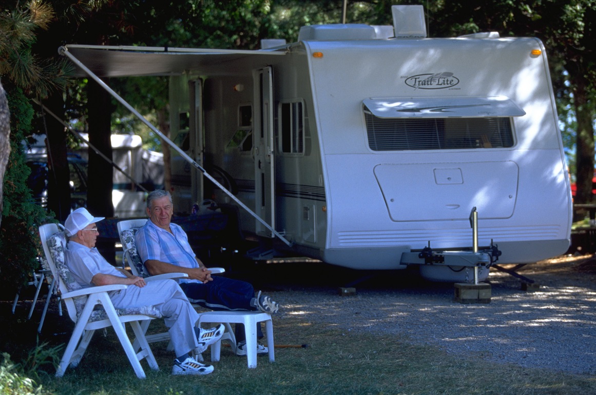 couple sitting beside RV on campsite
