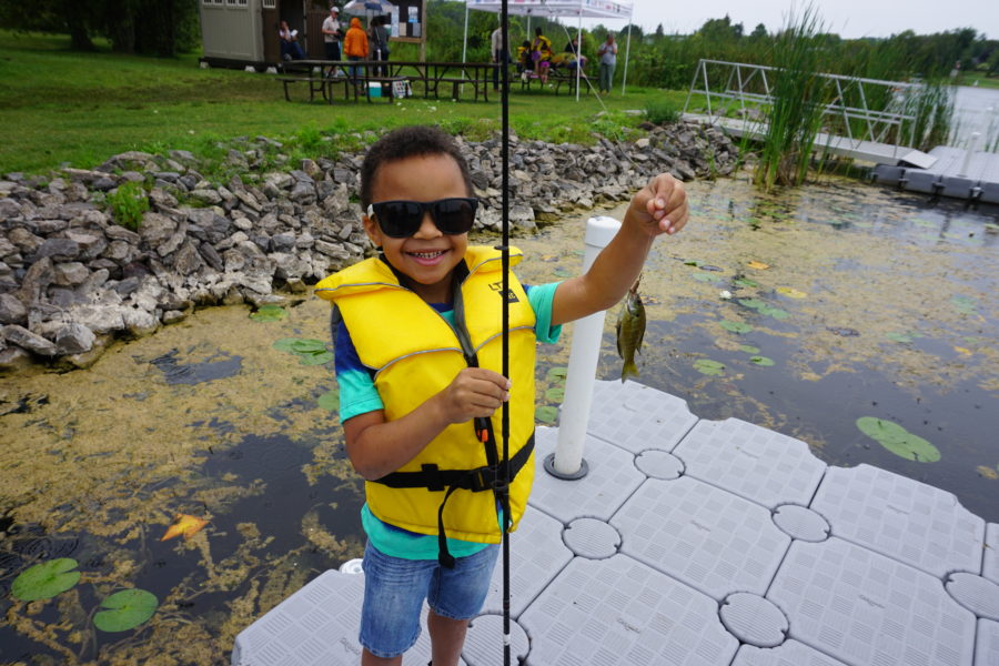 Child holding up a fish (and wearing some great sunglasses)