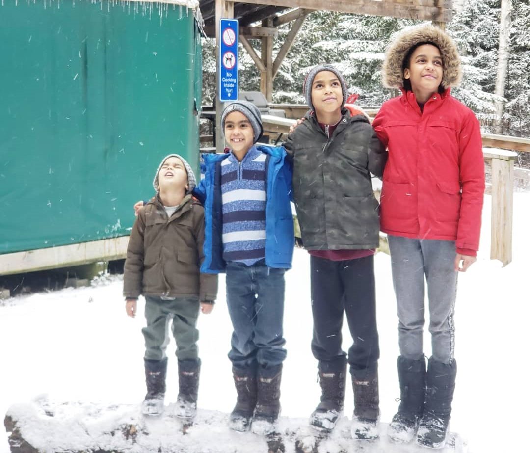 Four children by a yurt at MacGregor Point in the winter