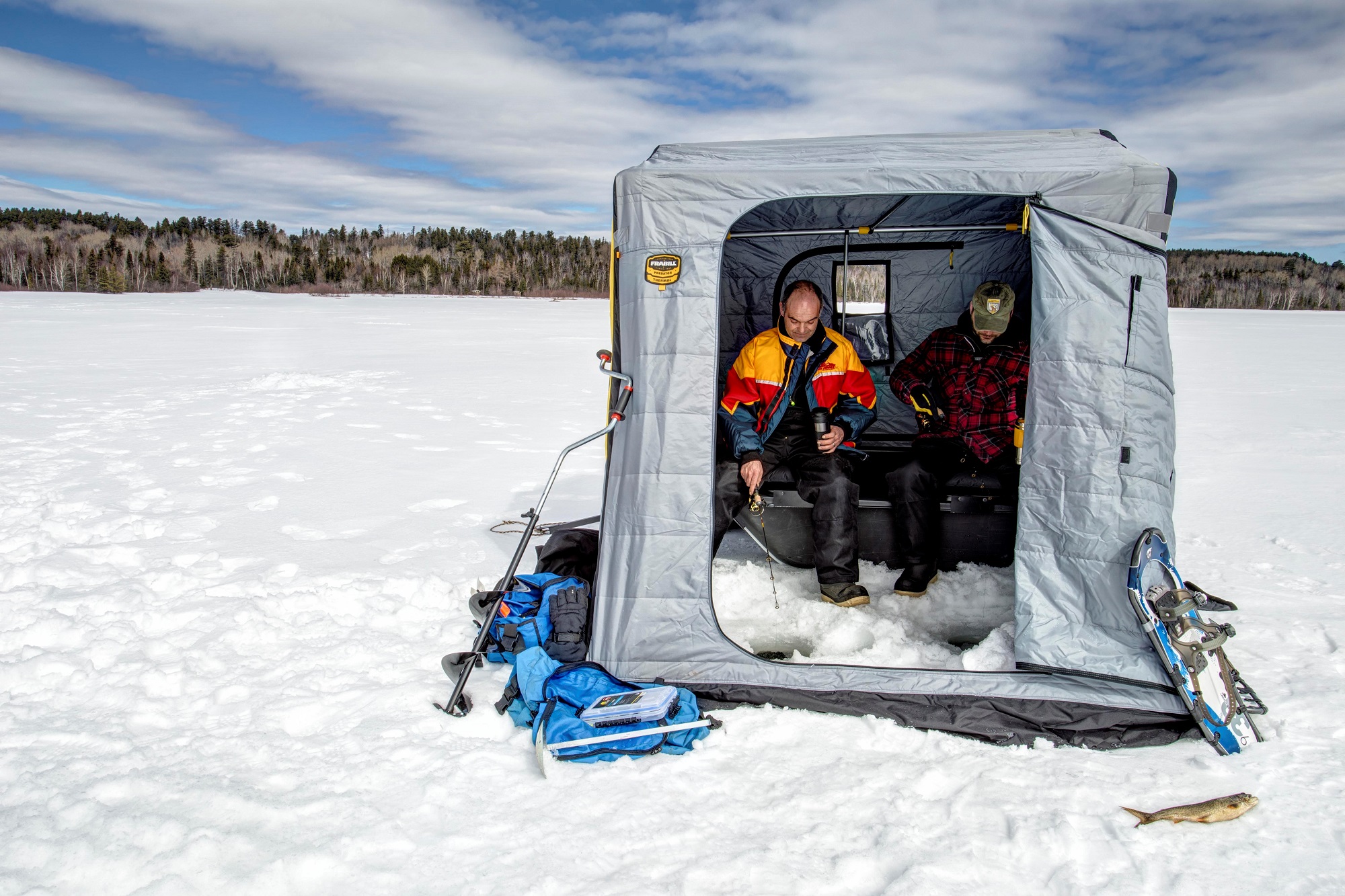 two men on frozen lake in ice fishing hut