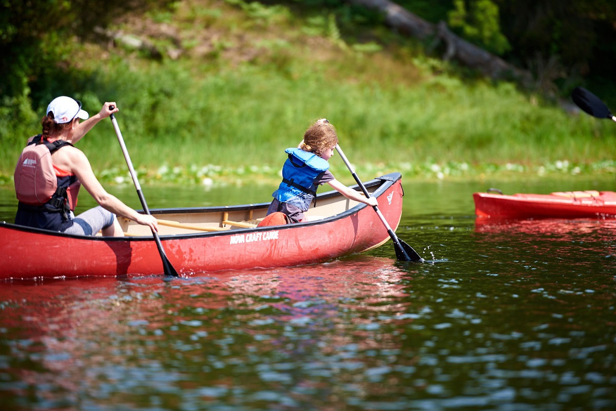 mother and child paddling canoe on river