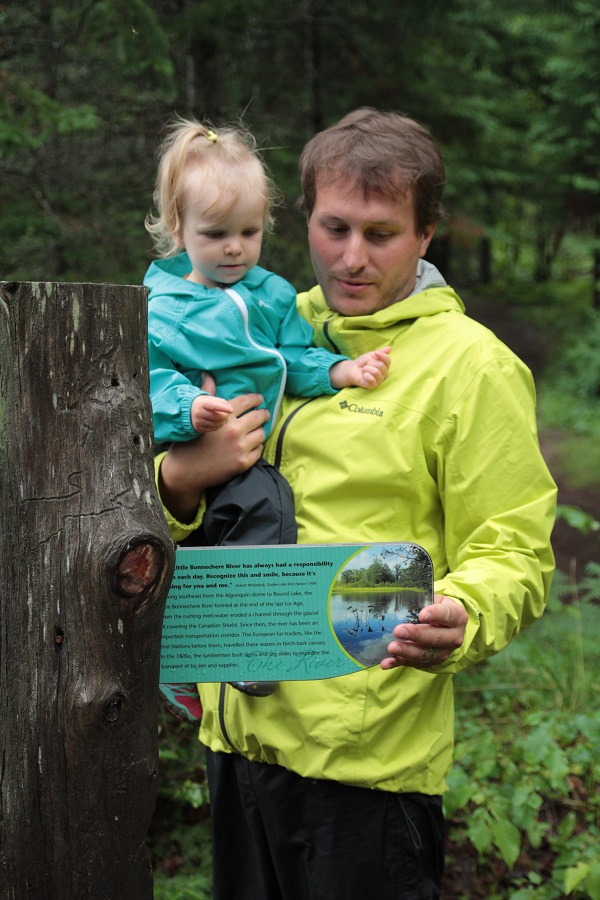 Father and daughter looking at trail signage.
