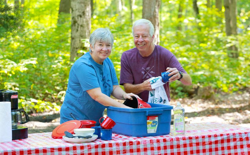 Couple washing dishes on campsite