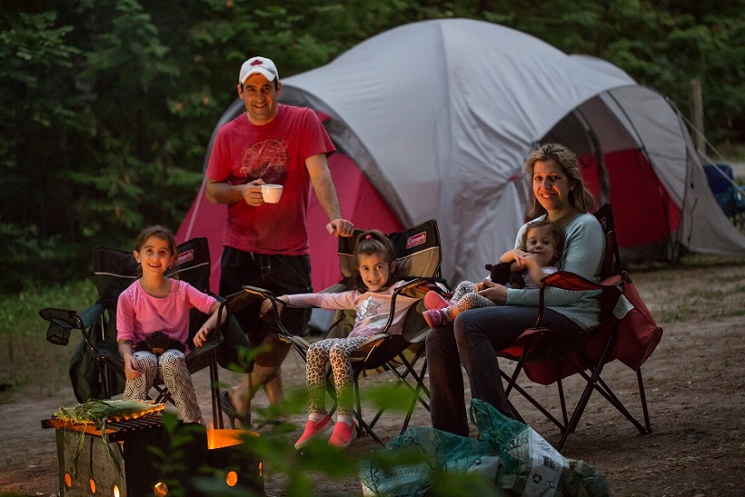 Family sits by the campfire in the evening