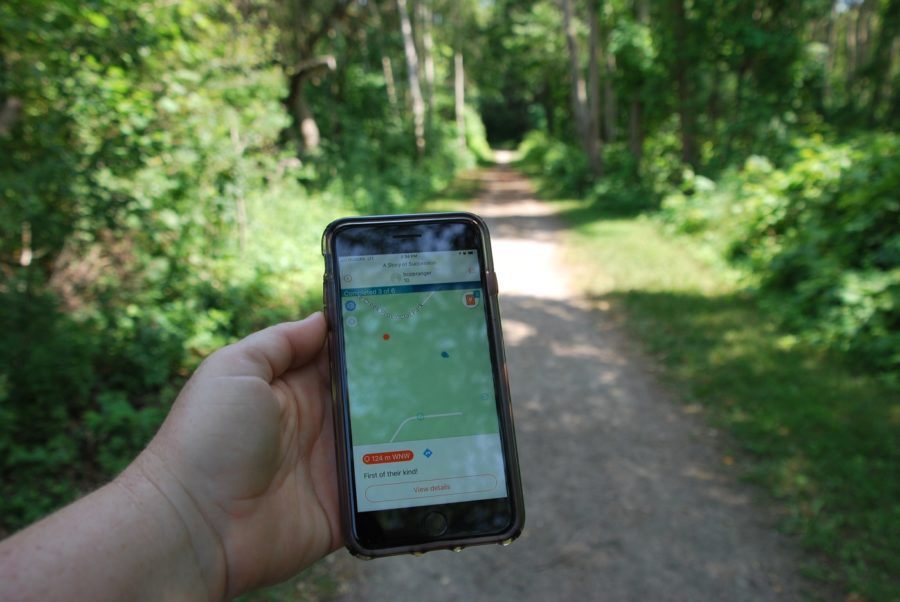 Une randonneuse tenant un téléphone cellulaire avec l’application Adventure Lab à l’écran