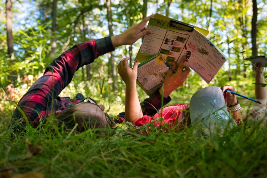 Adult and child laying in grass reading nature brochure