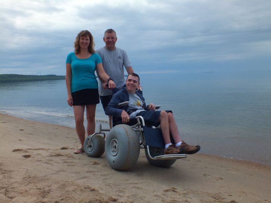 Park visitor in wheelchair on beach with two adult companions
