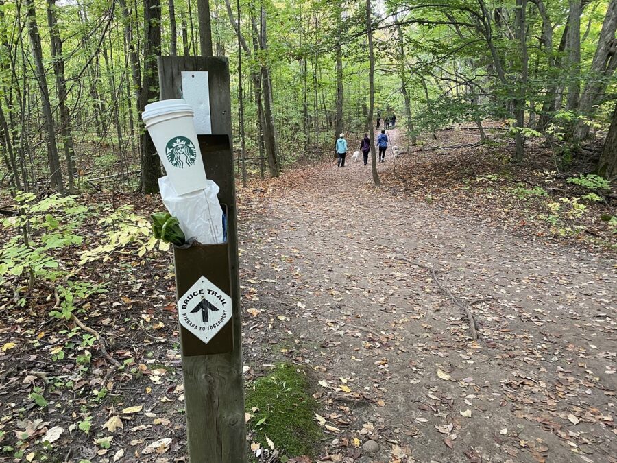 tasse de café sur un panneau de sentier d’un sentier de randonnée