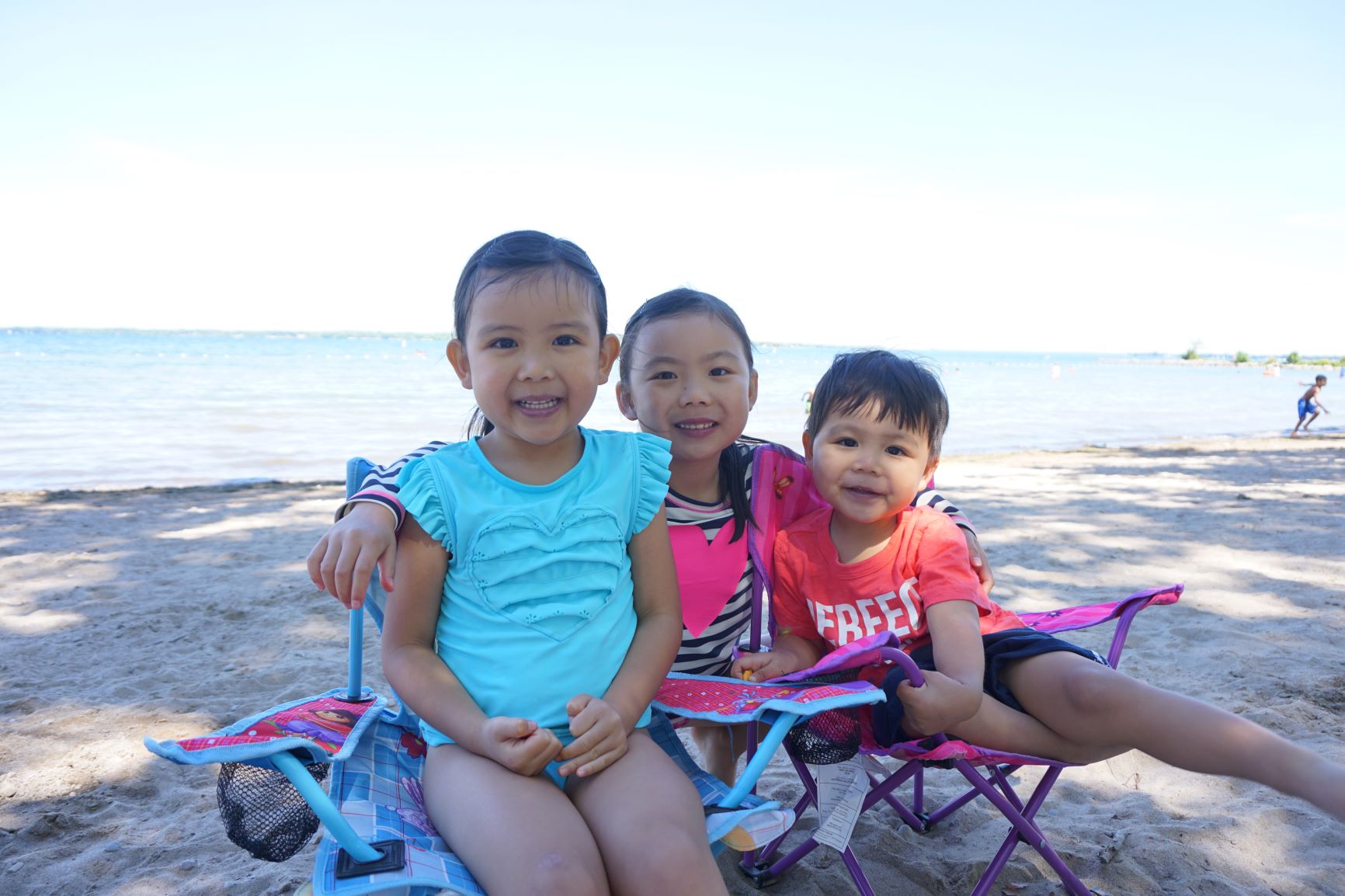 Trois enfants sur la plage, en été, le lac en arrière-plan.