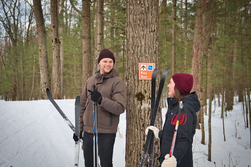 people holding ski equipment near trail