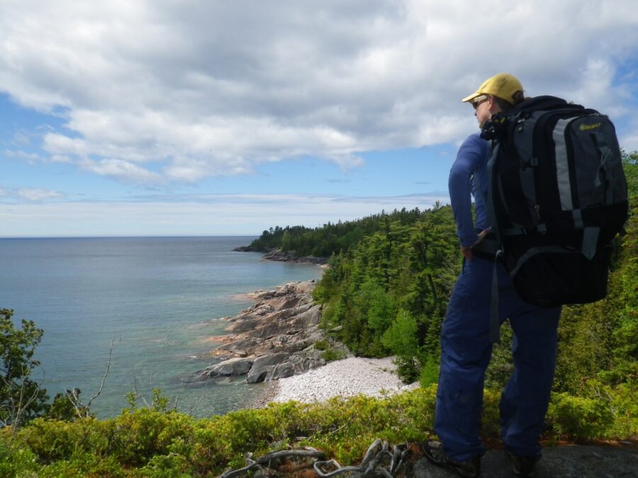 Kat wearing huge backpack and standing on outlook over Lake Superior