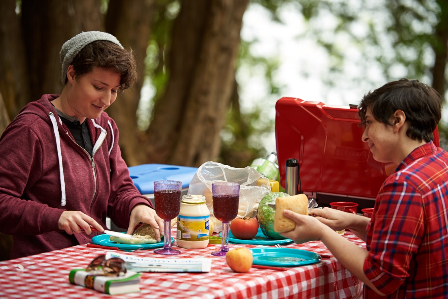 Two women enjoying a meal on a picnic table. 