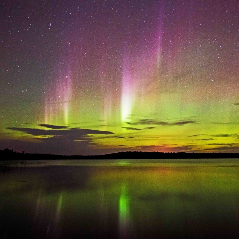 Purple and green northern lights over a lake in Quetico.