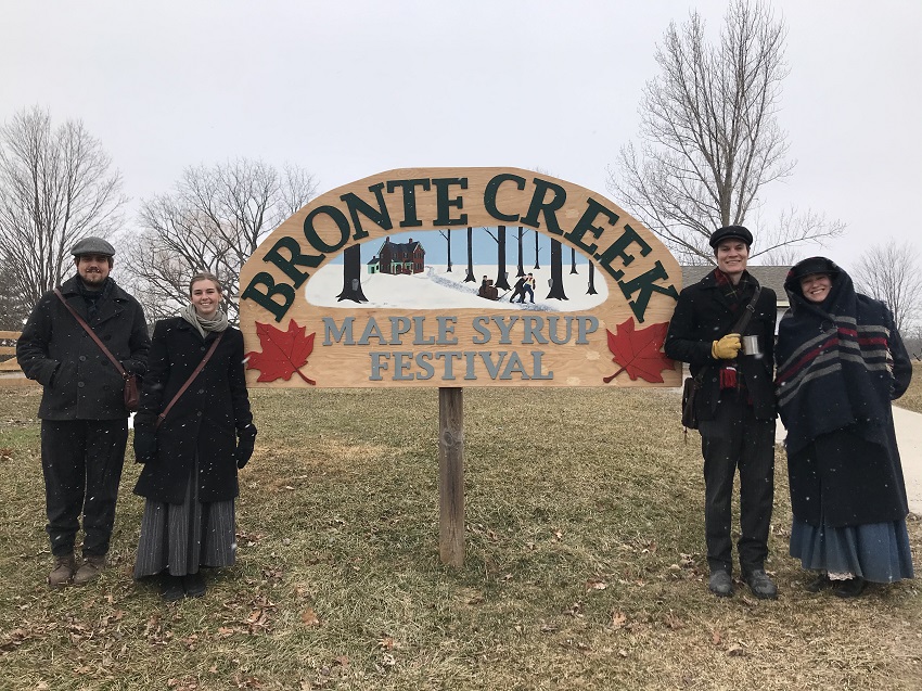 People in Victorian costume standing in front of a "Bronte Creek" sign