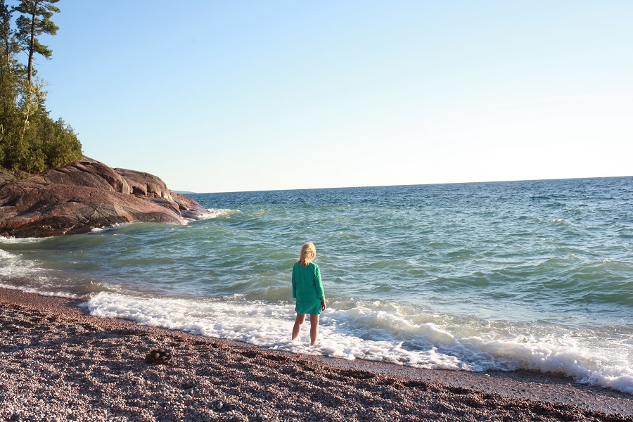 Femme debout, les pieds dans l'eau, à la plage.