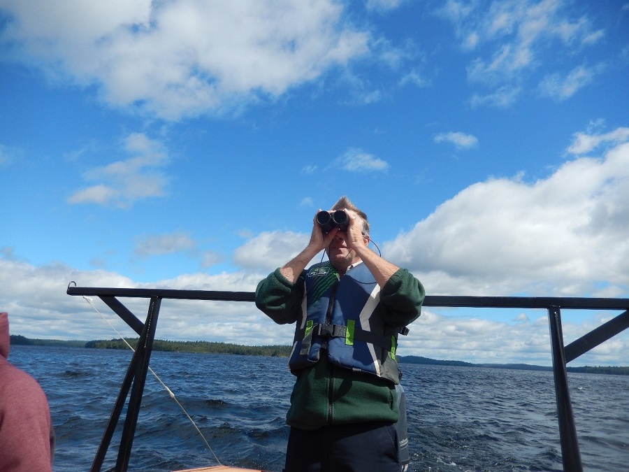 Man on a boat looking out of binoculars.