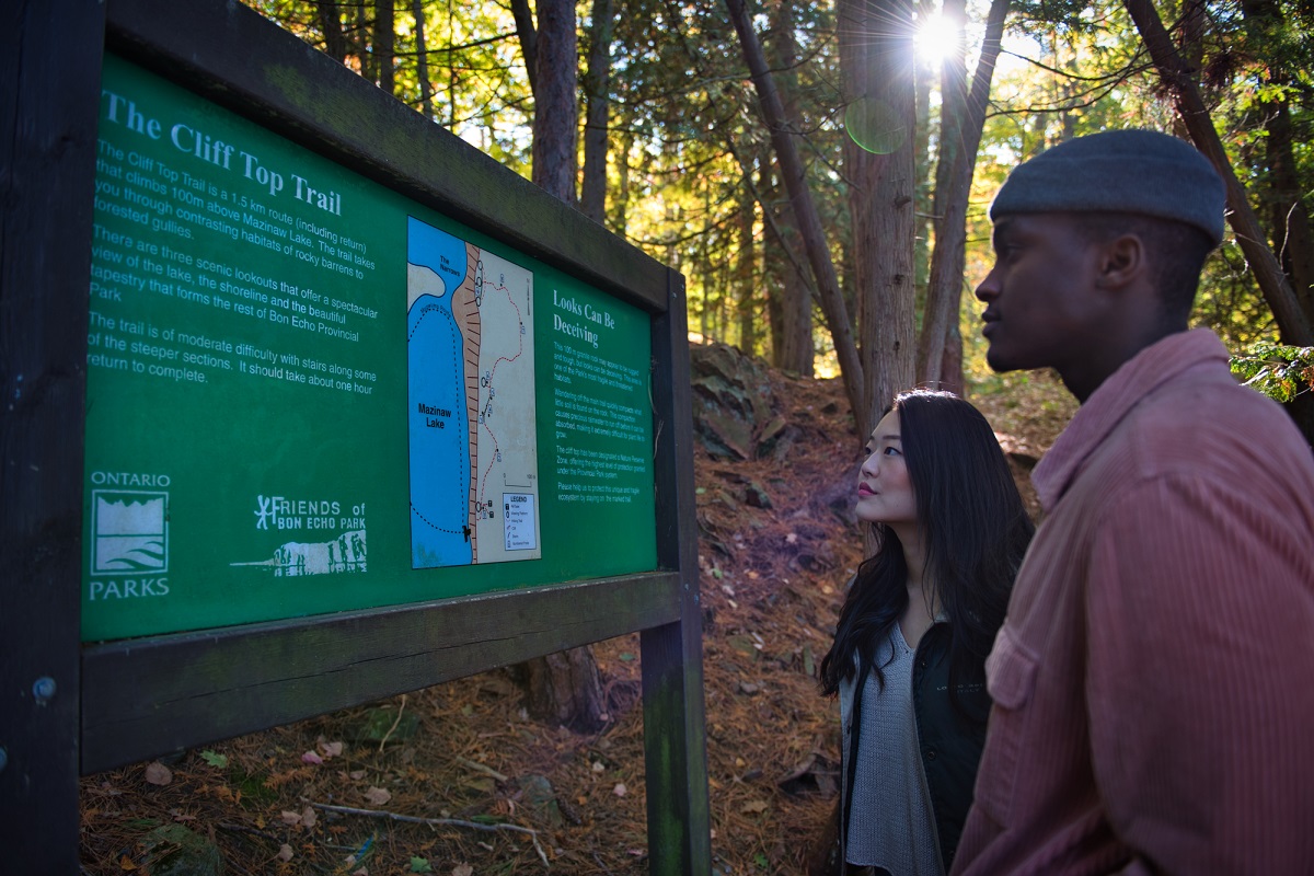 two hikers looking at map on sign