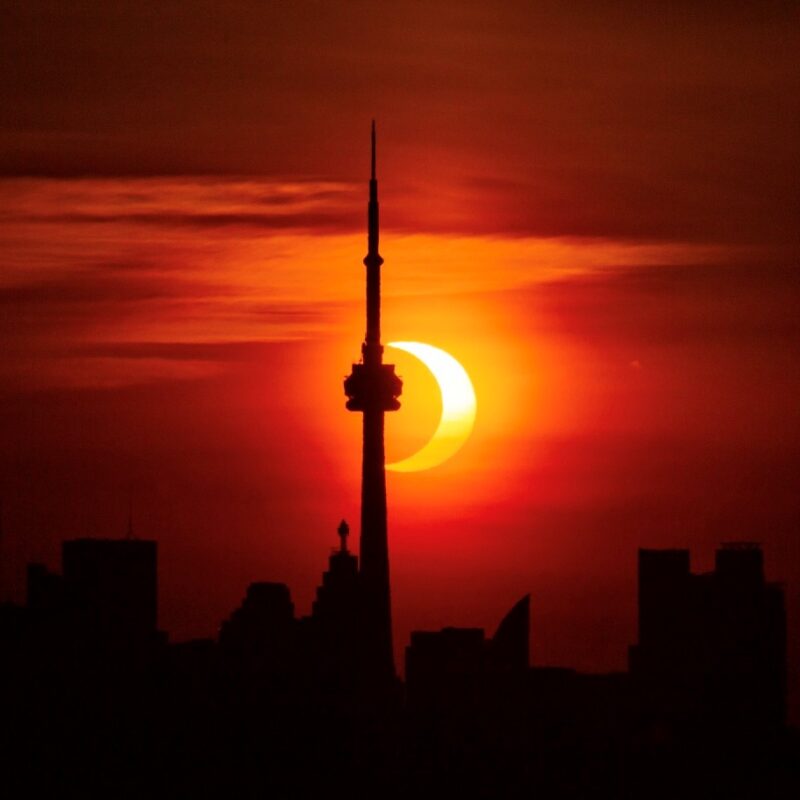 eclipse on red sky with CN Tower silhouetted in ofreground
