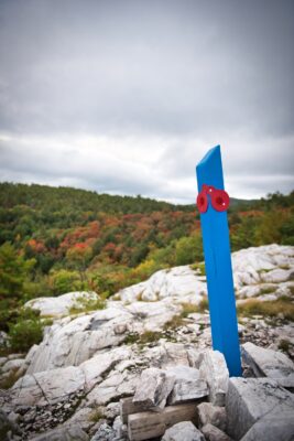 blue wooden post on white rocky crag
