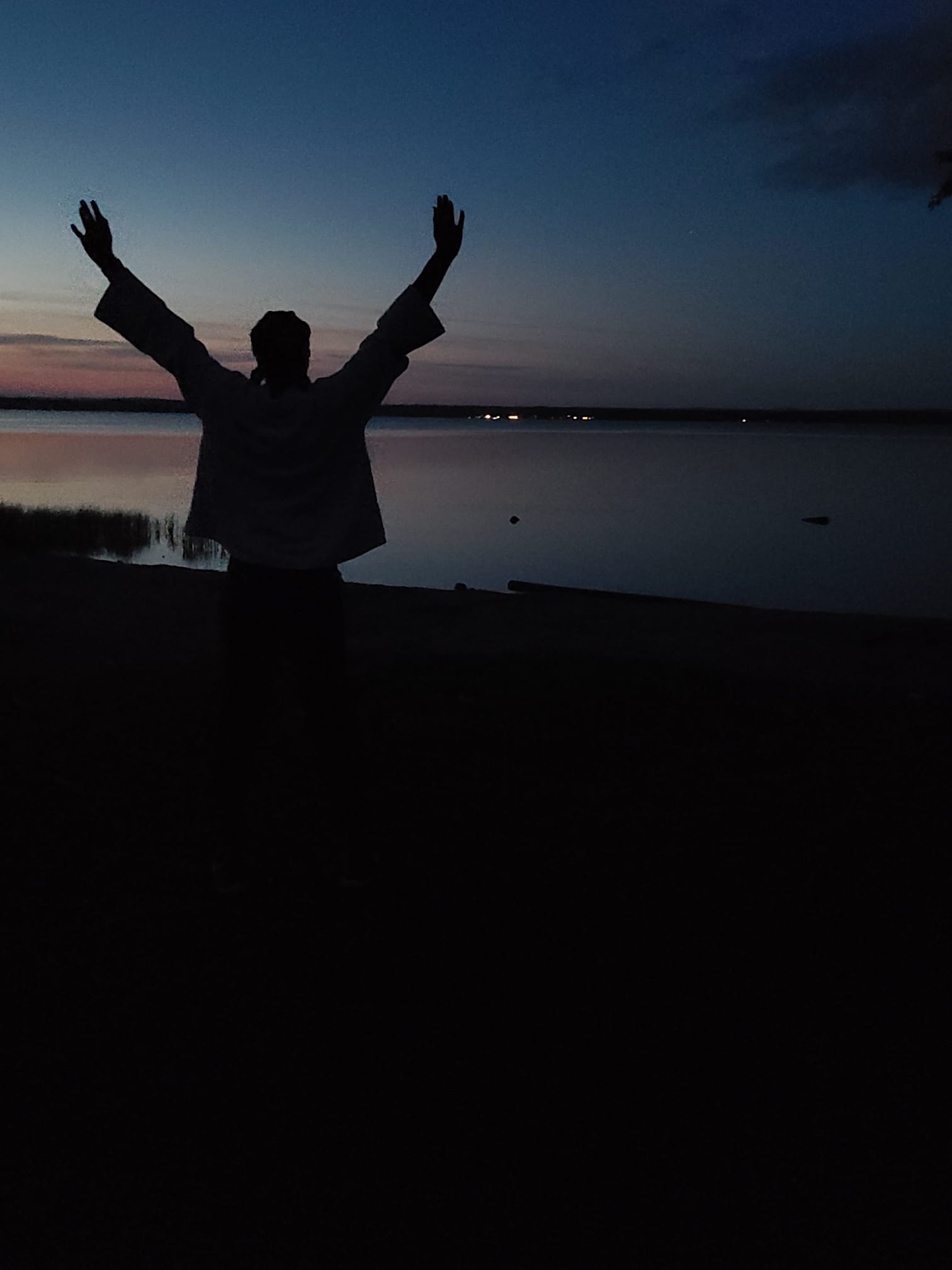 silhouette d’une personne aux bras tendus devant un coucher de soleil