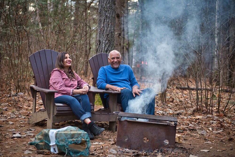 couple sitting on camp chairs around campfire
